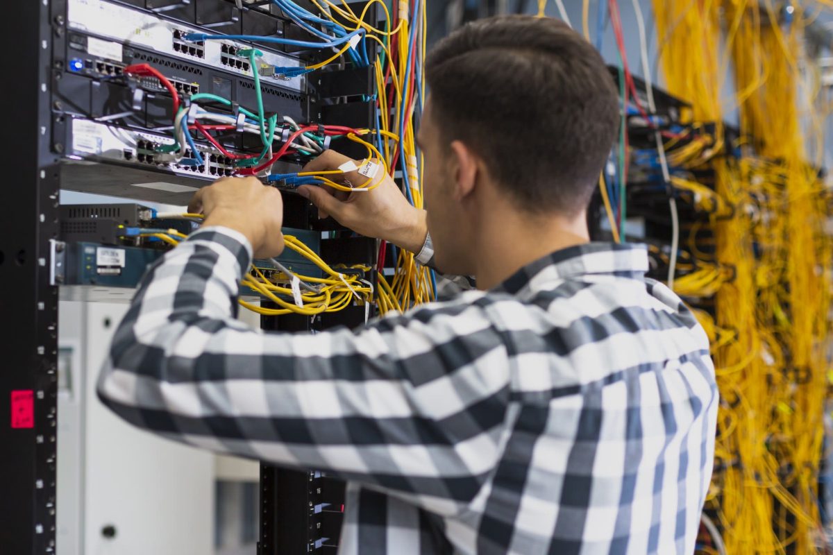 Un technicien en informatique en train de réparer un serveur avec des câbles réseau